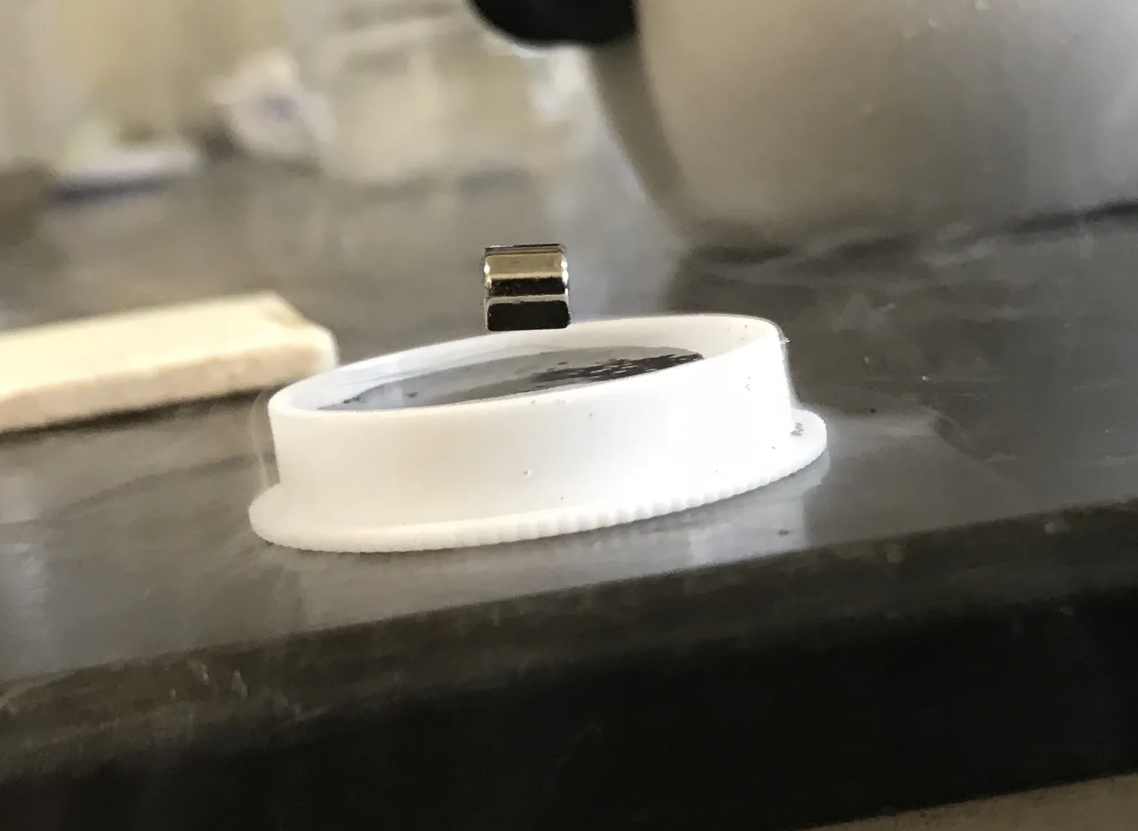 A small magnet held in mid-air above a superconducting disc chilled in liquid nitrogen, with cold vapour drifting across the bench